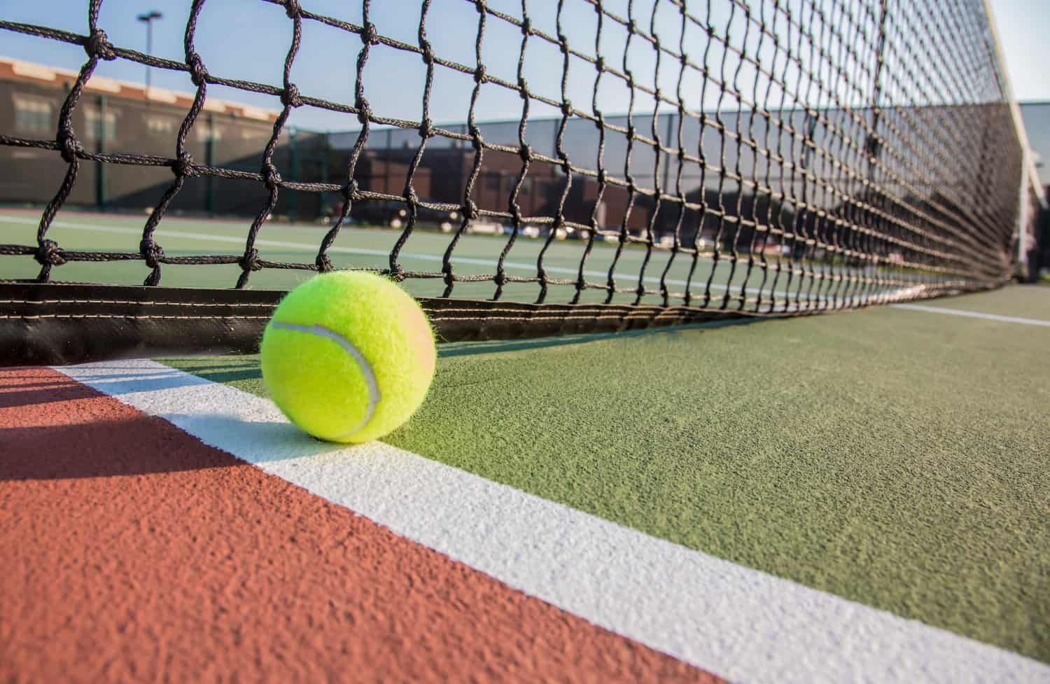 tennis ball next to black net on court